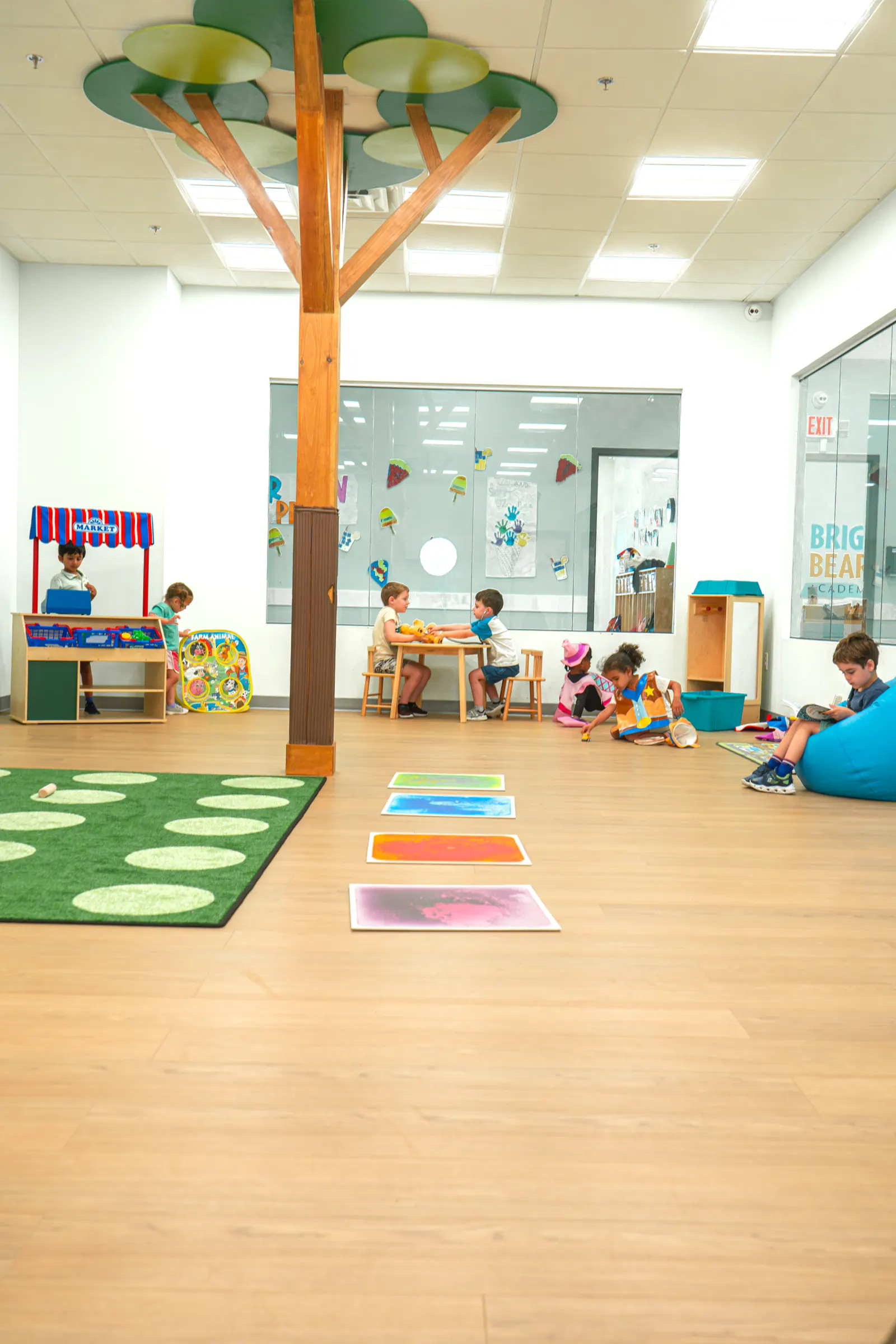 A bright classroom with a play tree and floor mats