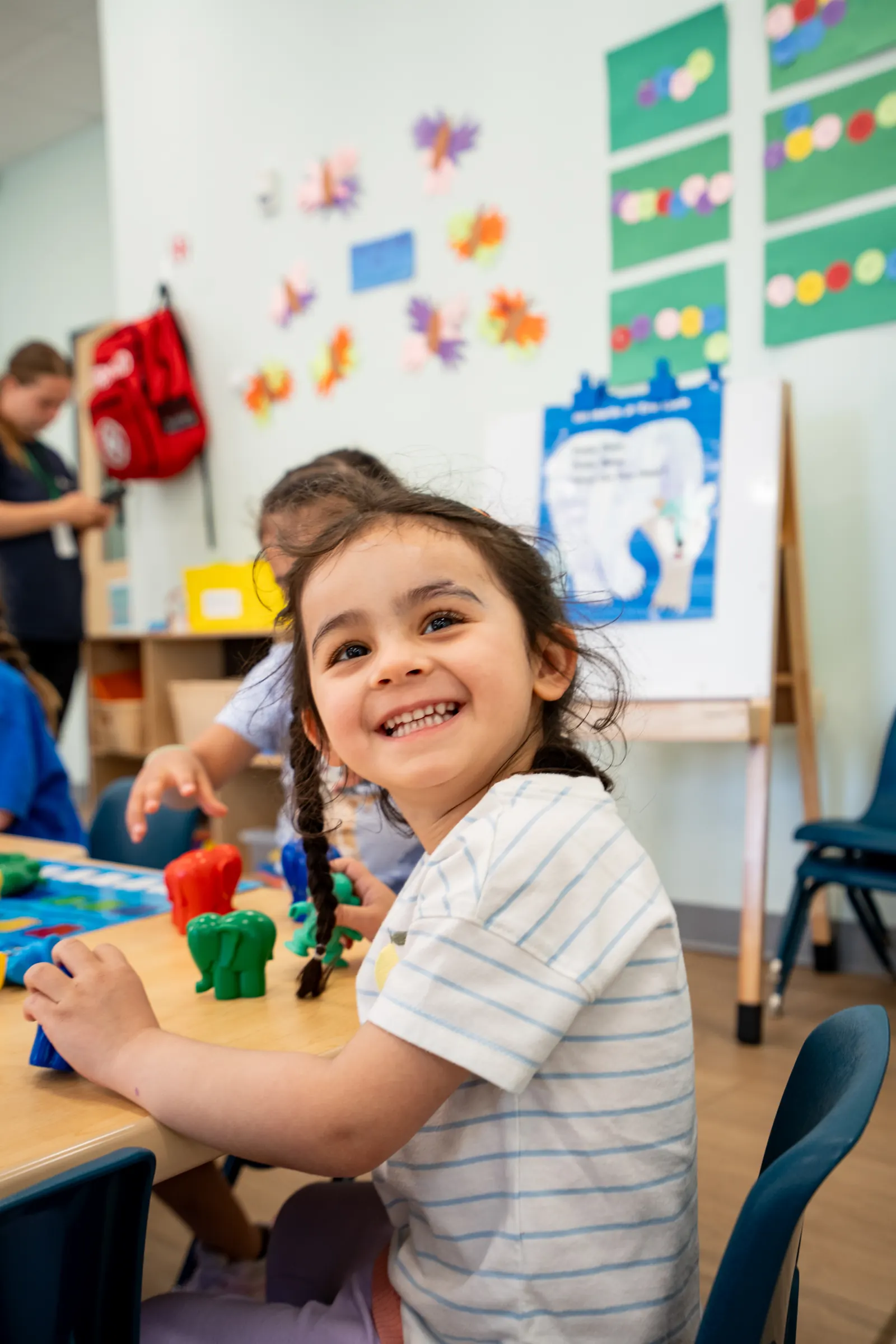 A smiling preschooler at a classroom table