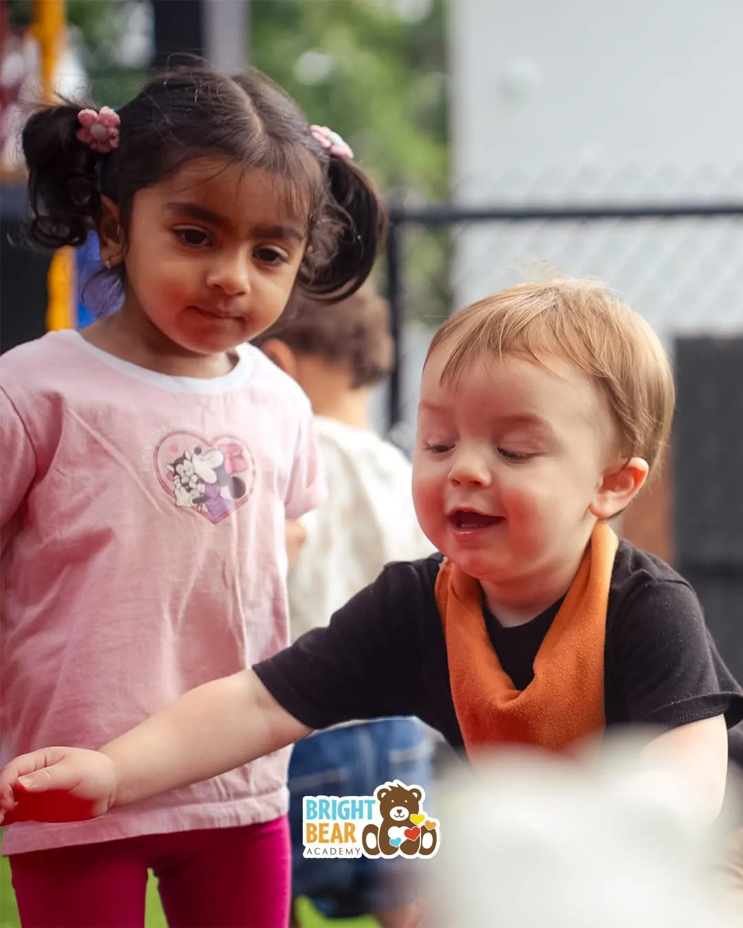 An infant smiling at a classmate